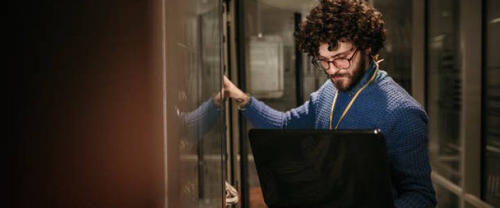 a person holding a laptop in a server room