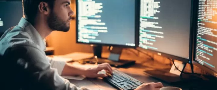 a person in front of 3 desktop computers