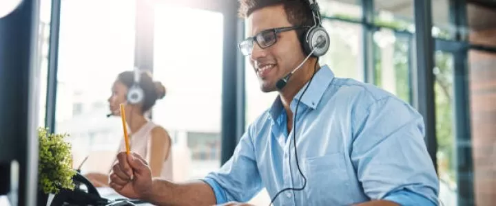 a man working in a call center with a female colleague in the background